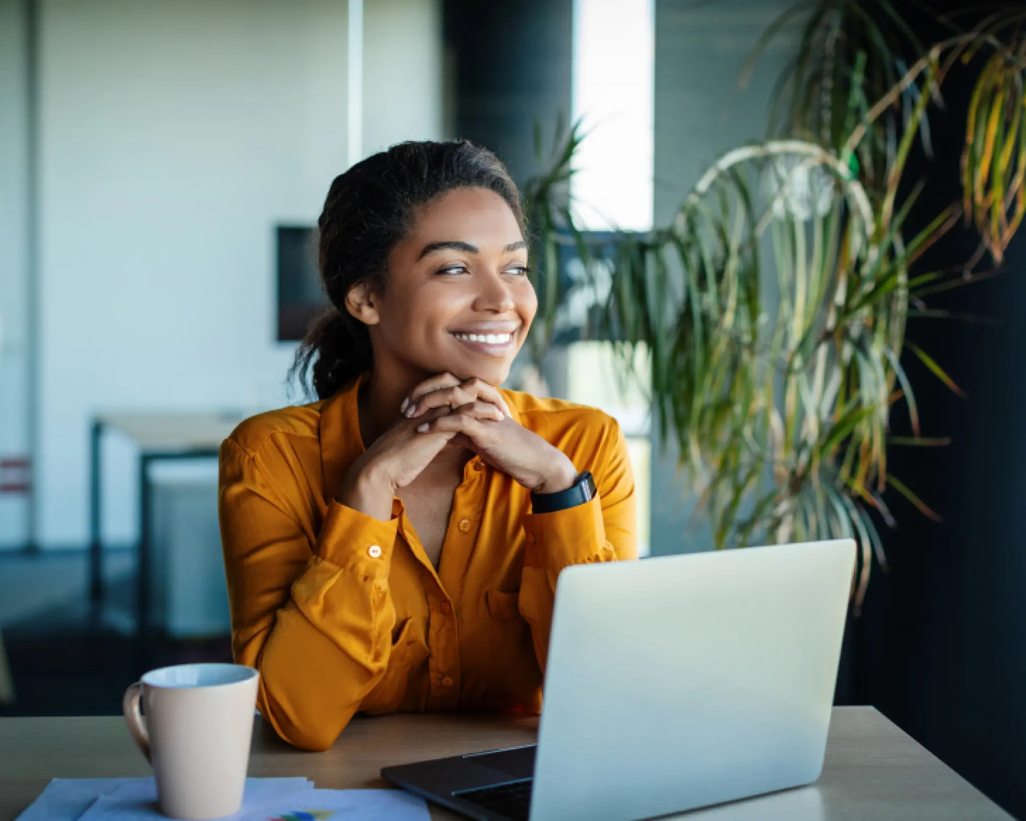 Lady in orange shirt smiling in front of laptop